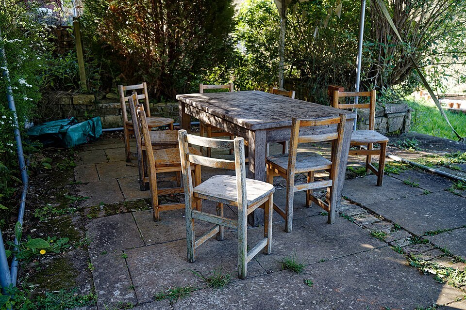 A table and chairs in a walled garden show why the occupied seating area matters as much as the tabletop.