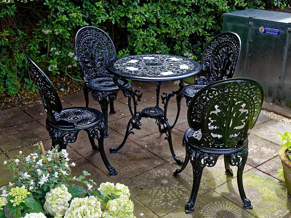 An outdoor table and chairs illustrate a complete furniture setting; cleaning methods must follow each actual piece and finish.