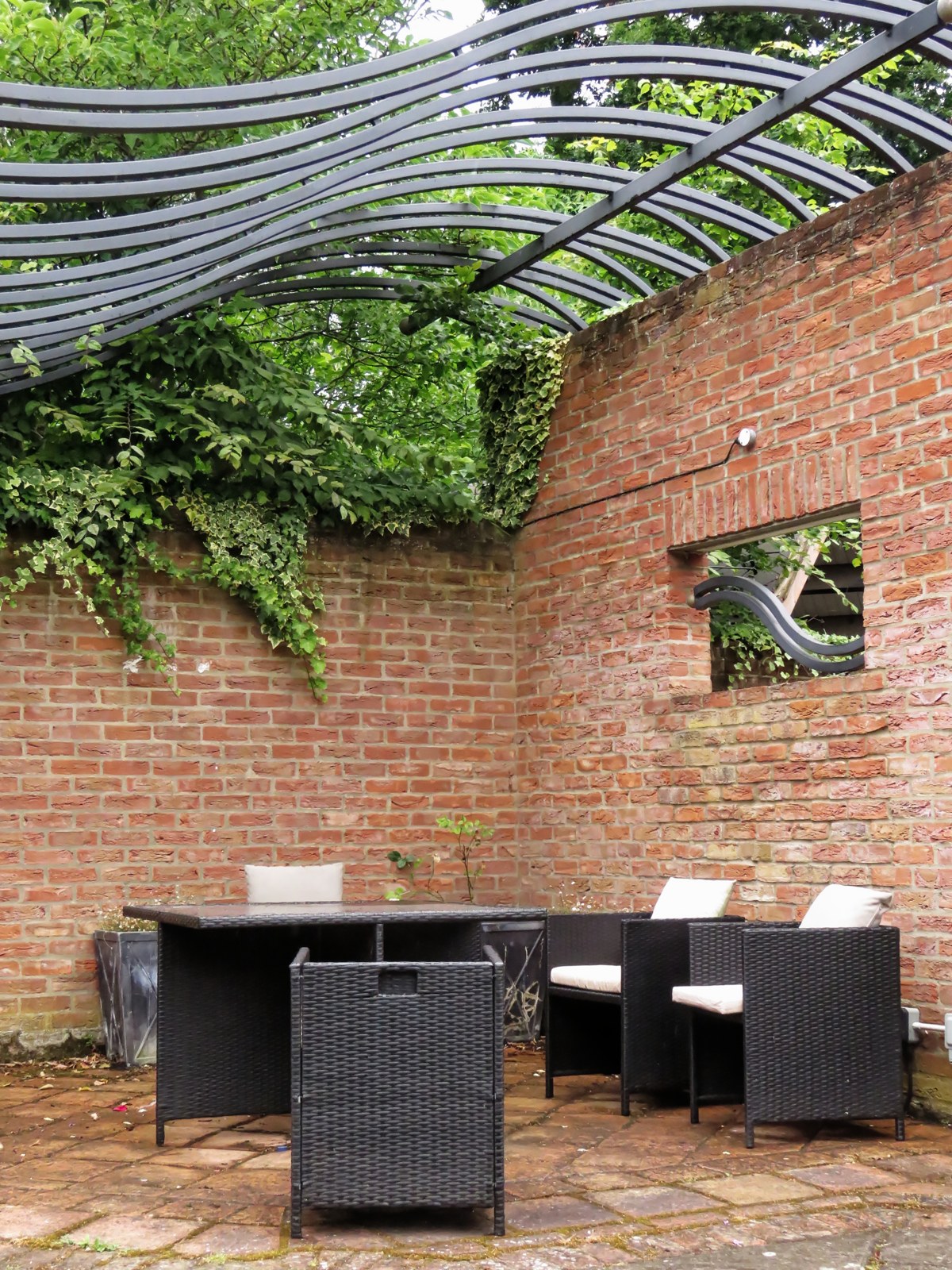 A planted brick courtyard with a table and woven chairs